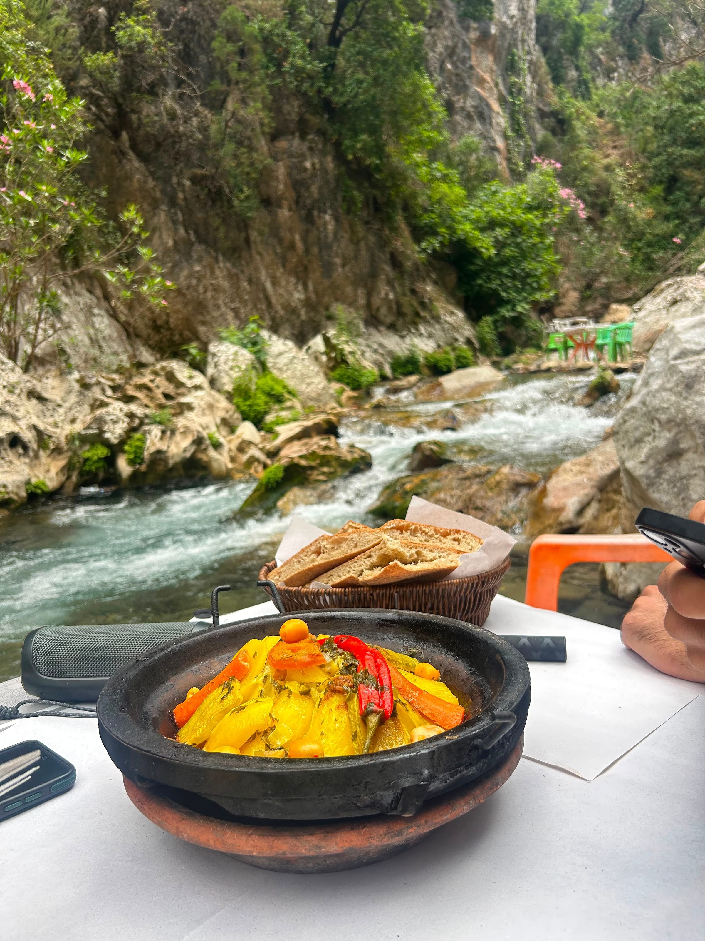 Una tajine e del pane appoggiati su un tavolo in riva al fiume